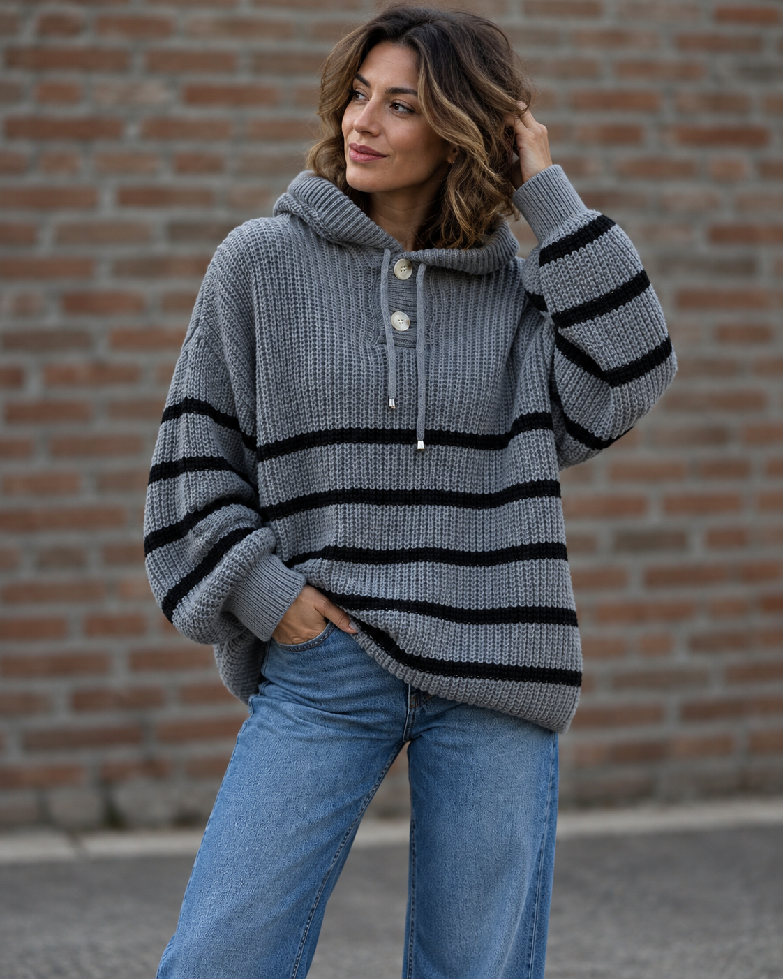 Noélla Montréal — gestreepte hoodie dark-grey, tweede volledige modelfoto, pose bij bakstenen muur